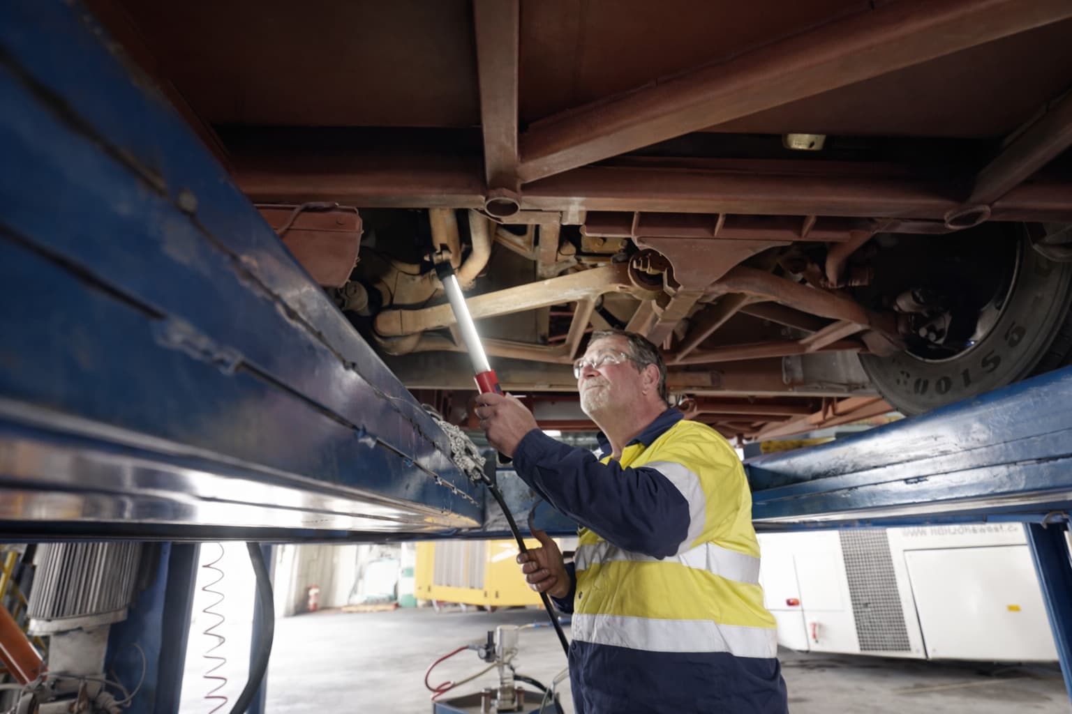 Horizons West mechanic inspecting the underbody of a coach raised on a hoist