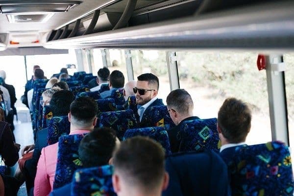 Wedding guests seated aboard a Horizons West coach, the groom turning to talk to the row behind